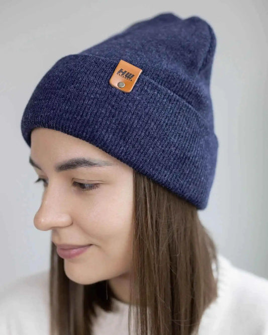 Person wearing a blue beanie with a brand logo on a plain background