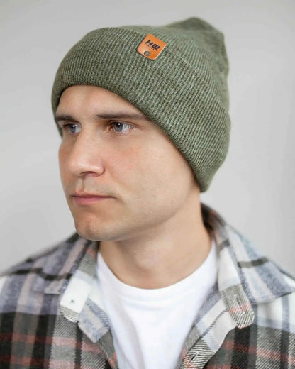 Man wearing a green beanie with a brand logo against a plain background