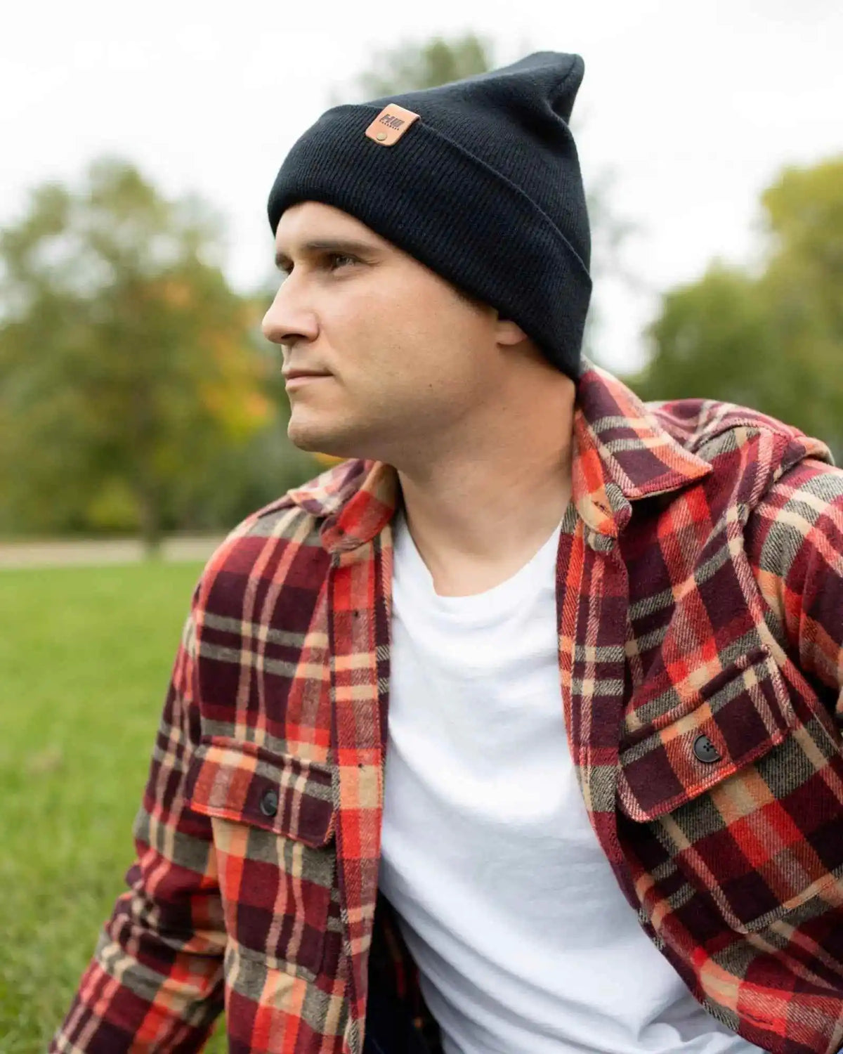 Man wearing a black beanie and red plaid shirt outdoors