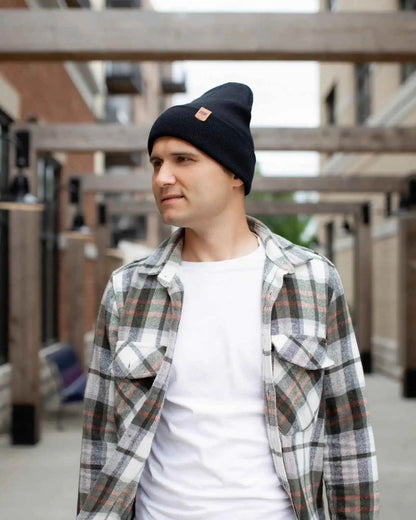 Man wearing a black beanie and plaid shirt in an outdoor setting