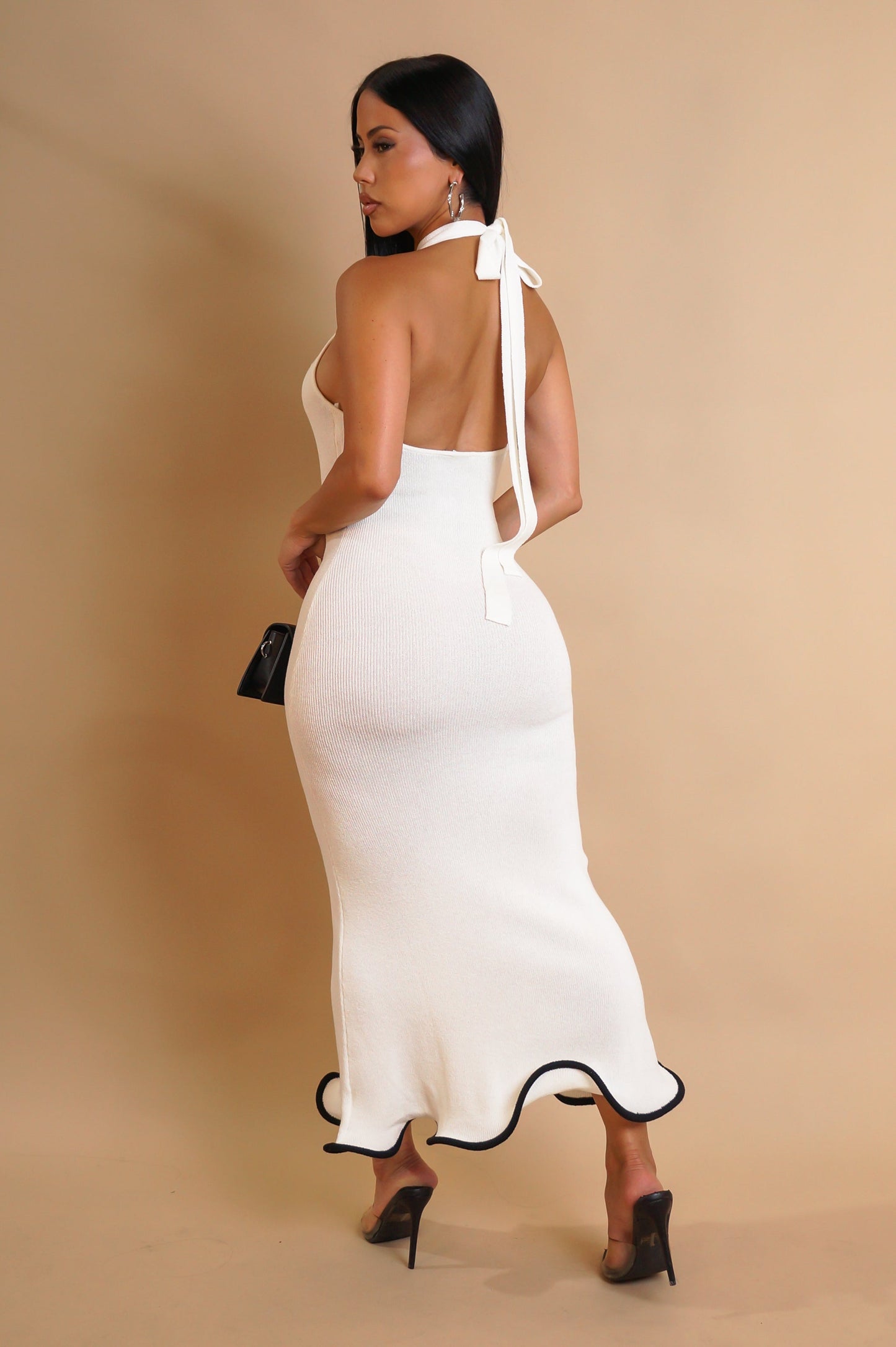 Woman wearing a white dress with a black trim on a beige background