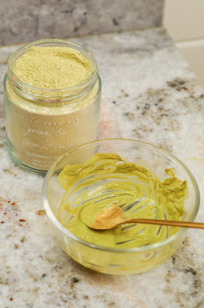 Jar of green tea ceremonially harvested powder on a marble surface with a small bowl of green tea powder.