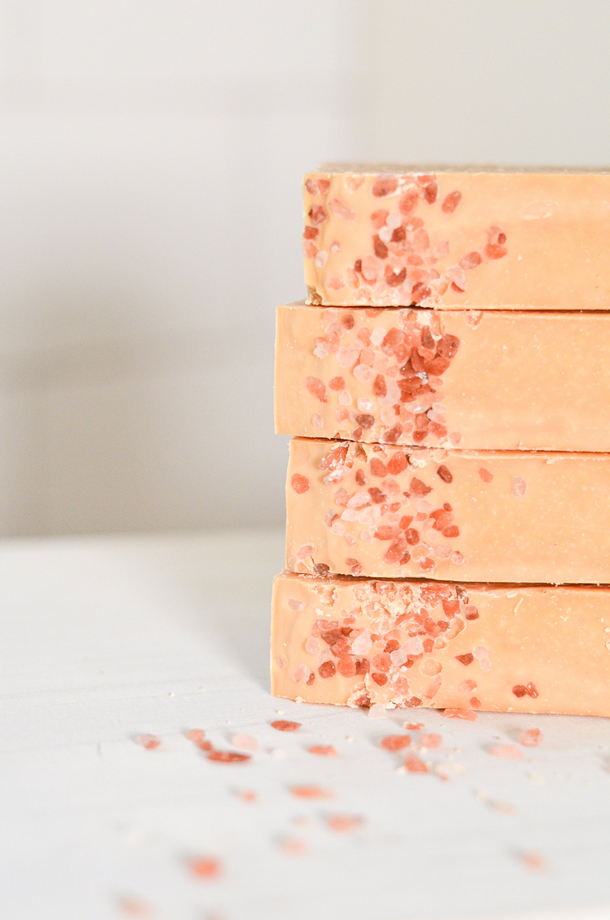 Stack of peach-colored soap bars with red specks on a light background