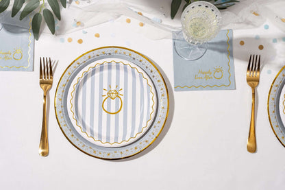 Round blue and white striped paper plate with a gold ring and Happily Ever After text on a matching napkin.