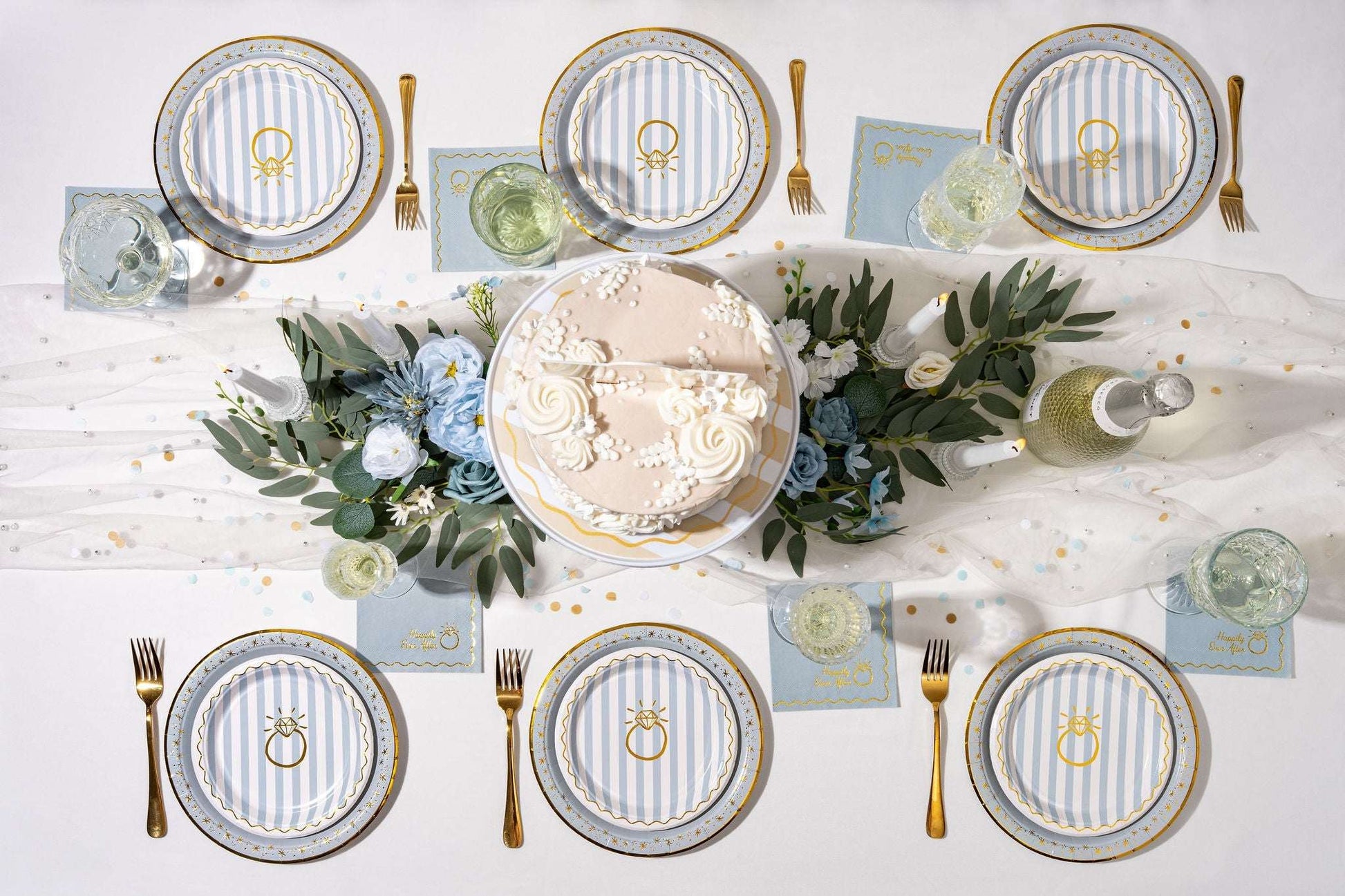 Six blue and white striped paper plates with gold ring graphics arranged on a table with a cake and floral centerpiece.