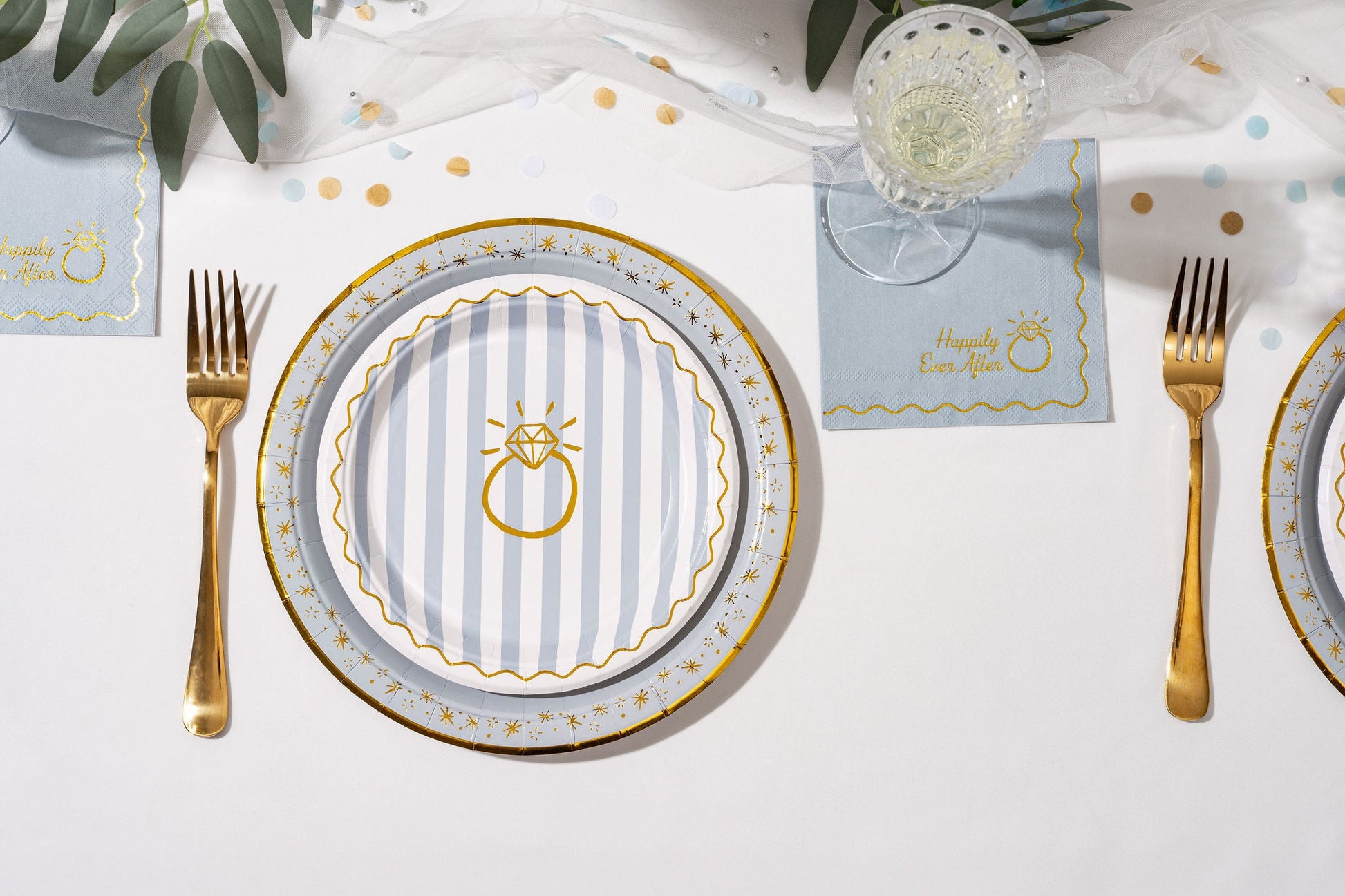 Dinner table setting with plates, cutlery, and place cards on a white tablecloth.