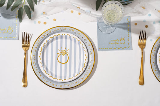 Dinner table setting with plates, cutlery, and place cards on a white tablecloth.