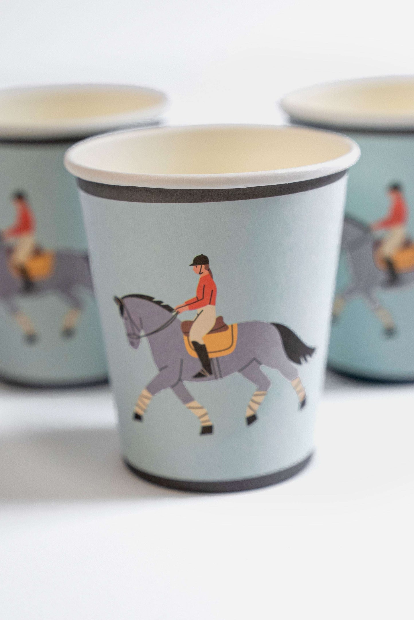 Set of paper cups with equestrian design on a light blue background