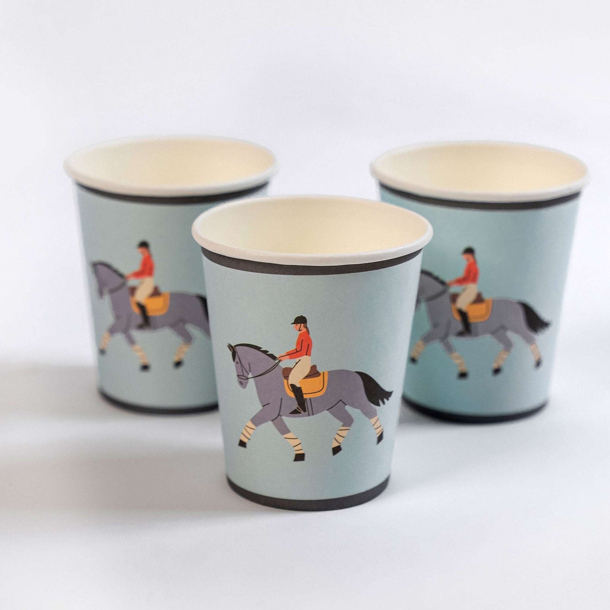 Three paper cups with horse and rider illustrations on a white background