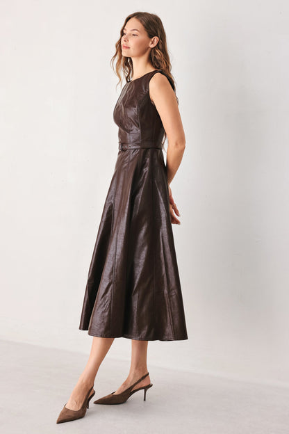 A woman modeling a sleeveless dark brown faux-leather midi dress with a structured bodice and flared skirt, paired with brown slingback heels, against a plain light gray studio background.