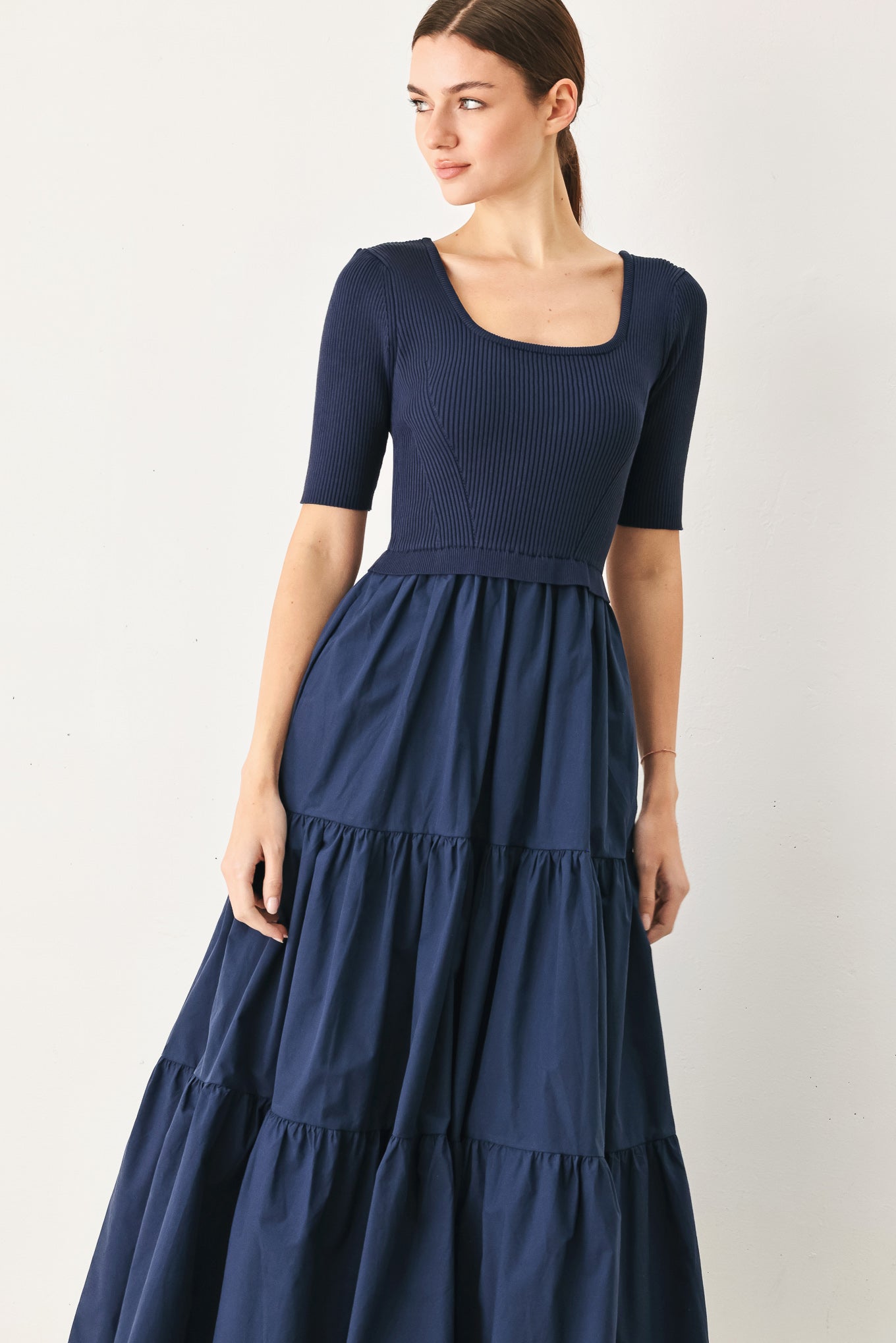 Woman wearing a navy blue dress with a plain background