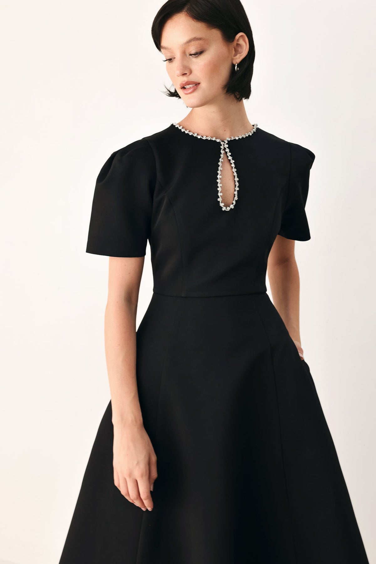 Black midi dress shown from the front with a jewel-trimmed keyhole neckline, puff sleeves and defined waist.