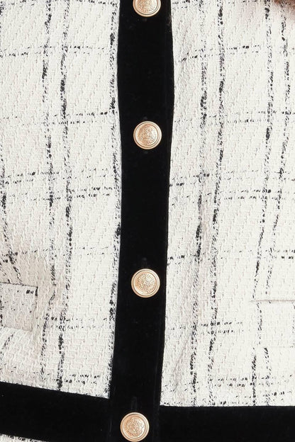 Close-up of a black belt with gold buttons on a textured white and black background