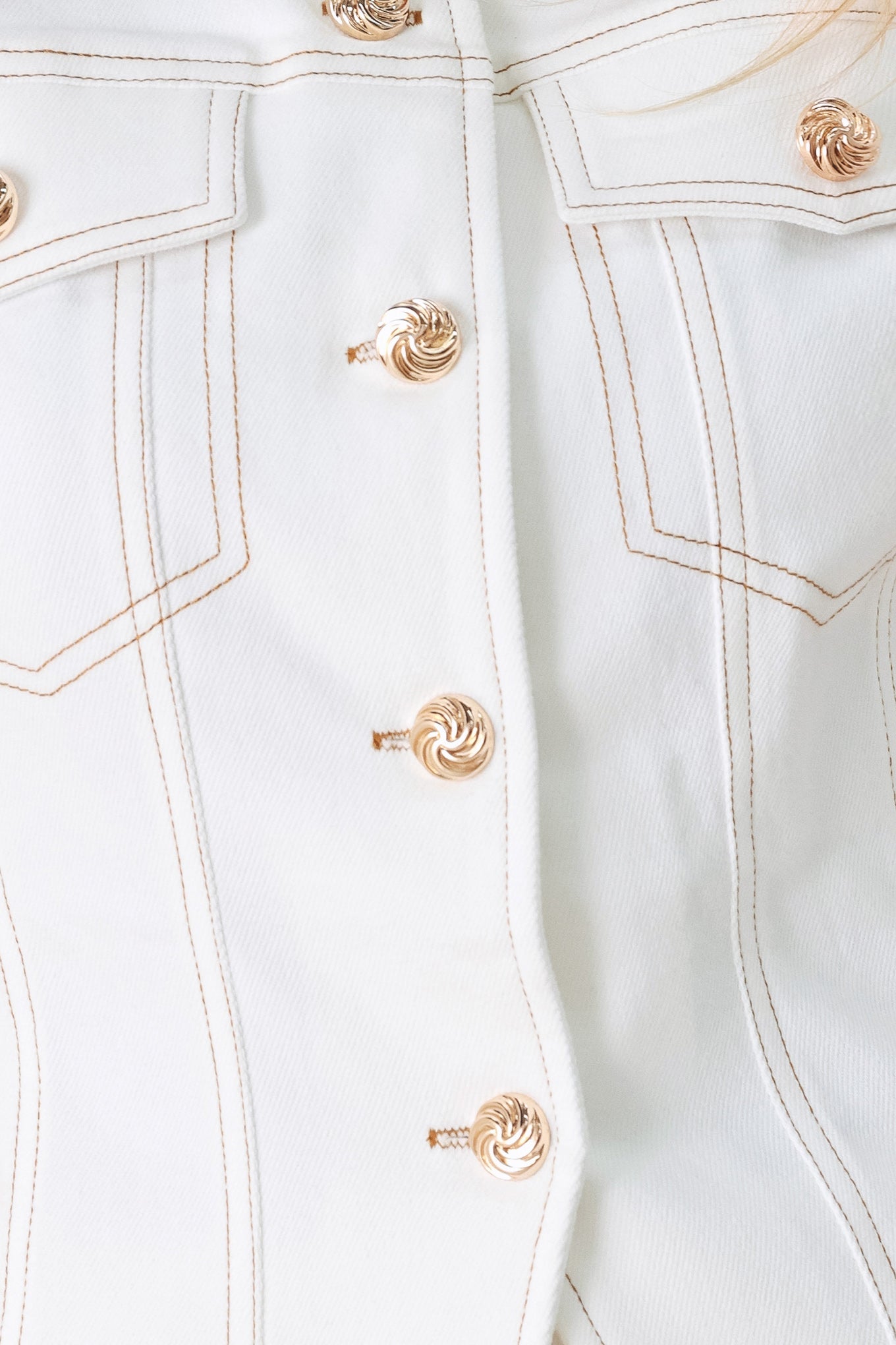 Close-up of a light blue denim jacket with gold buttons