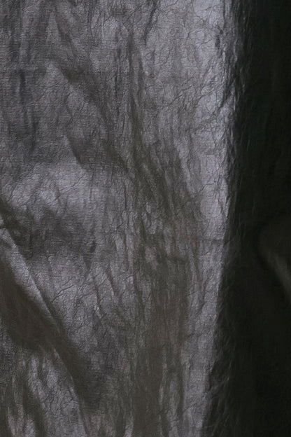 A close-up of a dark gray to black sheer mesh or netted fabric with a crinkled texture, filling the frame.