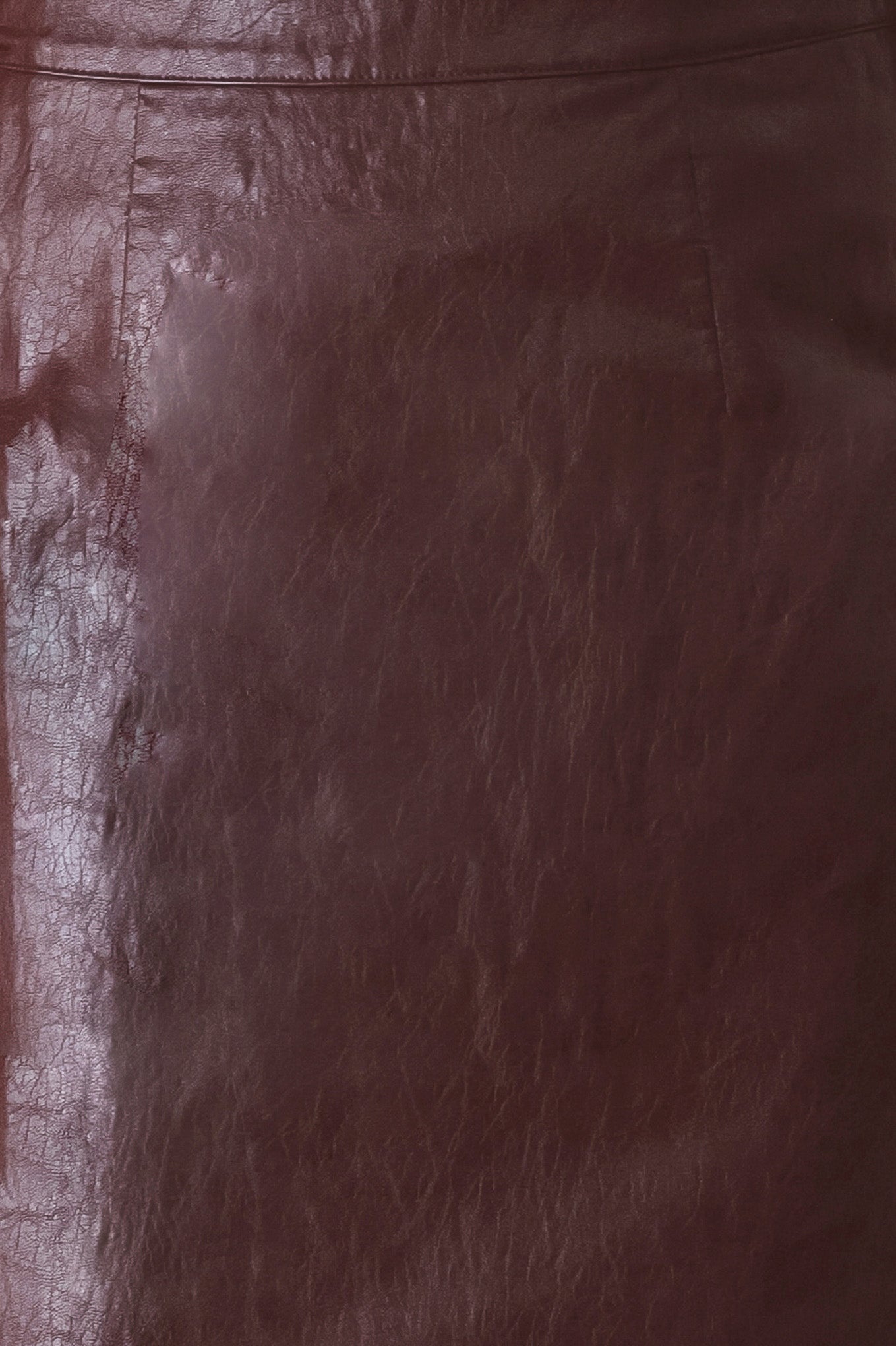 A close-up of a dark brown leather surface with visible texture, grain, and a seam line near the top.