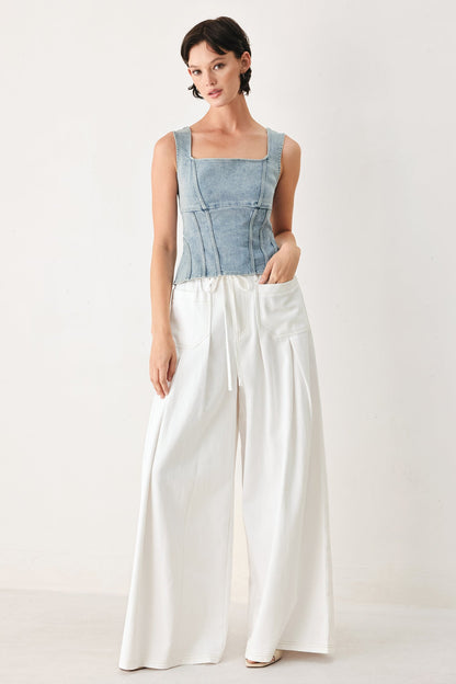 Woman wearing a blue top and white pants on a white background
