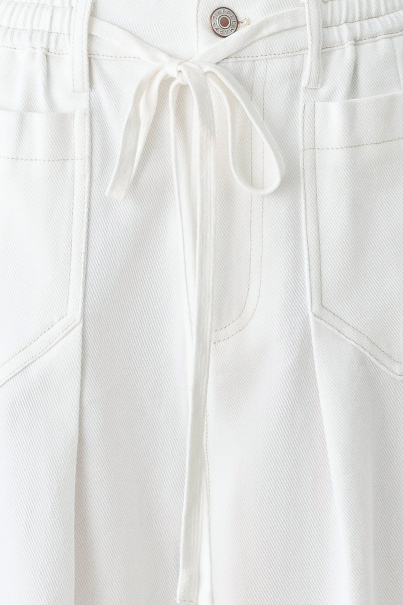 Close-up of white pants with a button and drawstring on a white background
