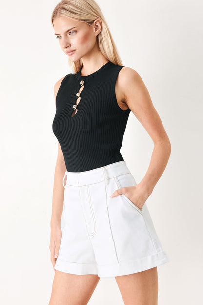 Woman wearing a black sleeveless top and white shorts on a plain background