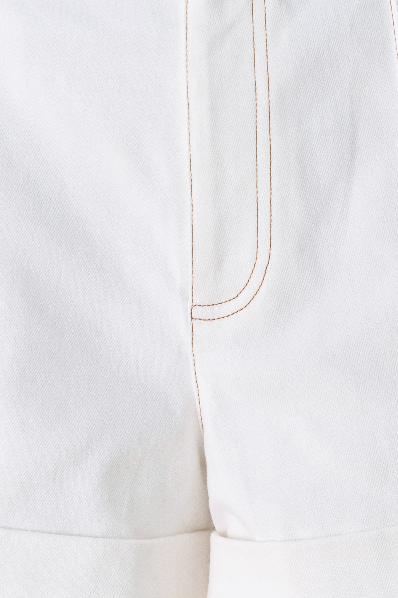 Close-up of a white garment with a gold thread seam on a white background