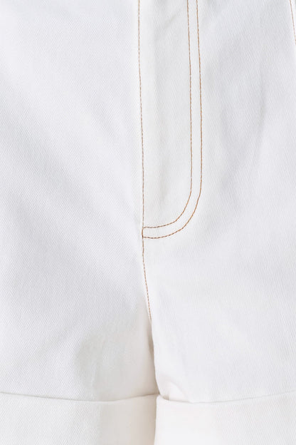 Close-up of a white garment with a gold thread seam on a white background