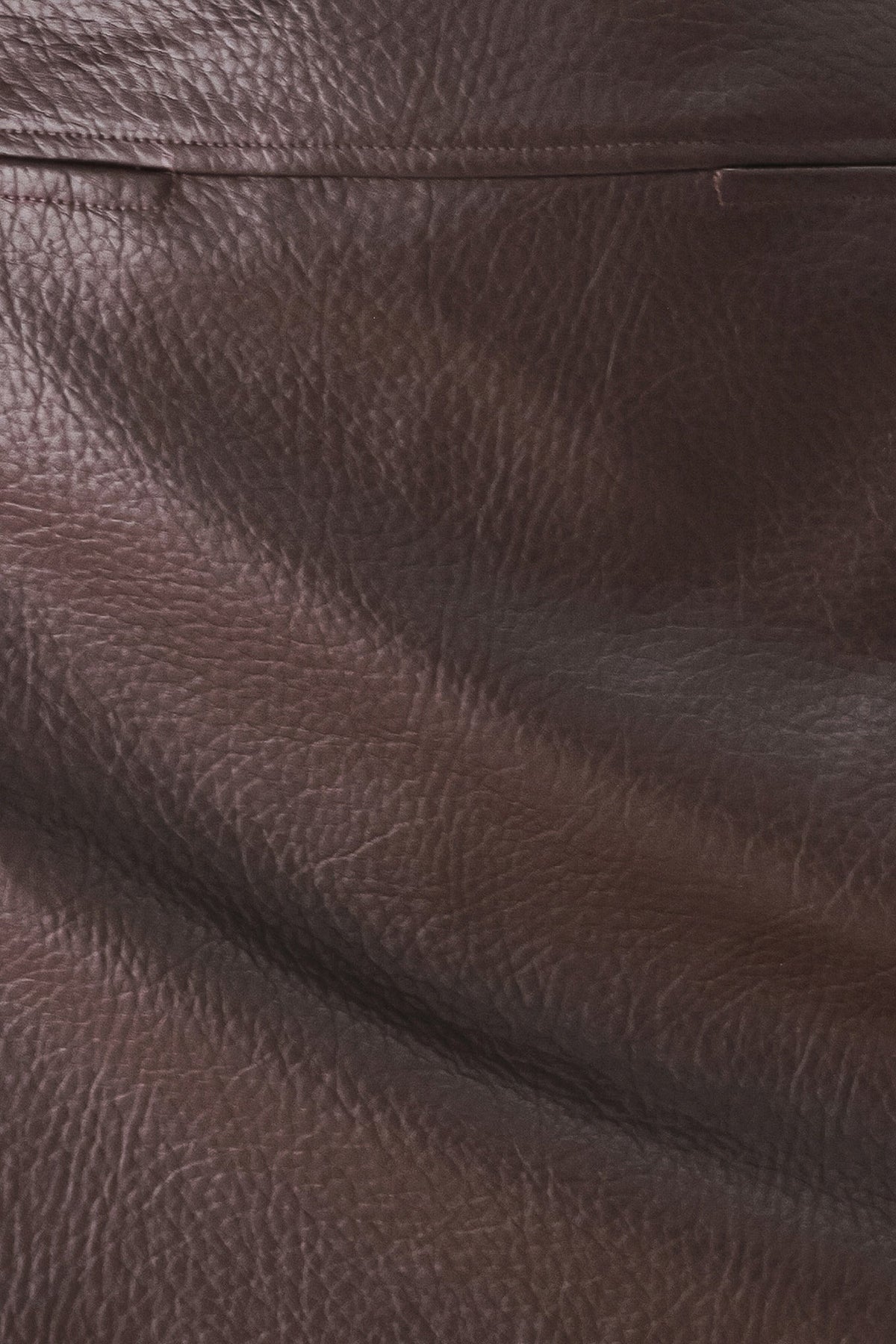 A close-up of dark brown textured leather with visible grain and a horizontal seam.