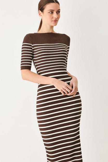 A woman modeling a fitted ribbed knit midi dress with horizontal brown and off-white stripes, featuring a boat neckline and short sleeves, against a plain light gray studio background.