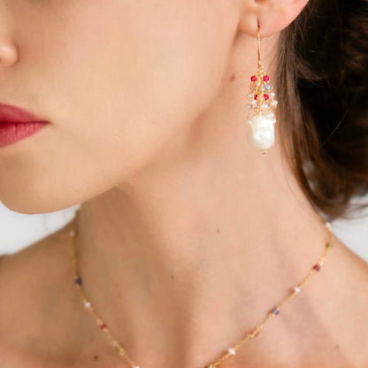 Close-up of a person wearing pearl earrings and a matching necklace.