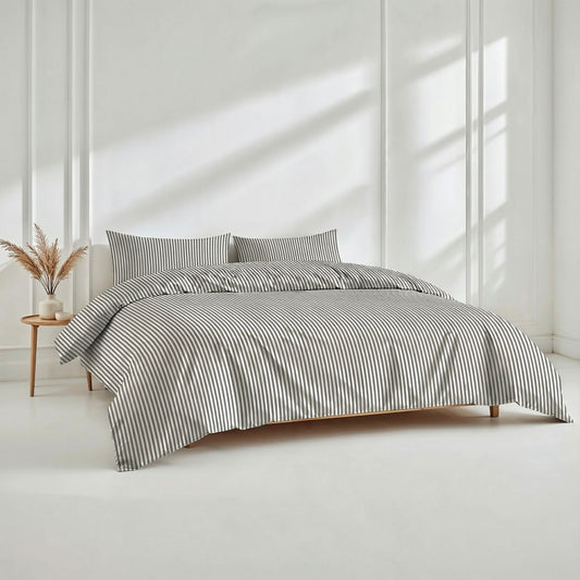 Bed with striped bedding in a bright room with sunlight filtering through.