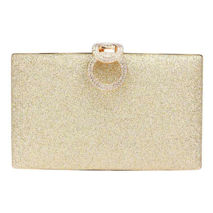 Gold glitter clutch with a decorative ring on a white background