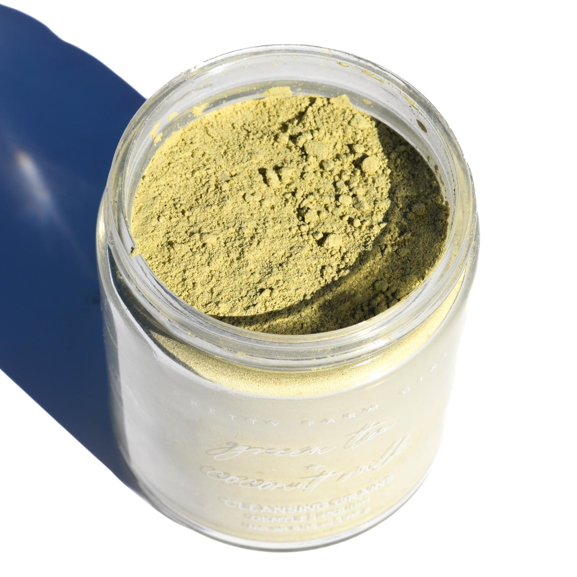 Jar of green powder with a blue background