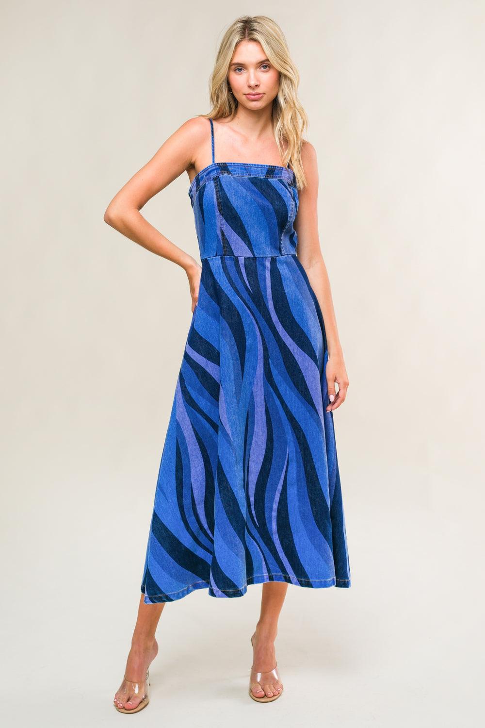 Woman wearing a blue and black patterned dress against a plain background