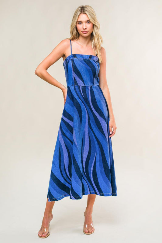 Woman wearing a blue and black patterned dress against a plain background
