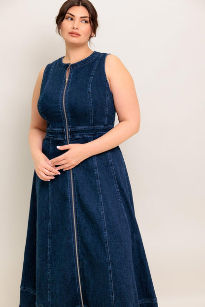 Woman wearing a blue denim dress against a plain background