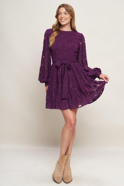 Woman wearing a purple dress with long sleeves on a white background