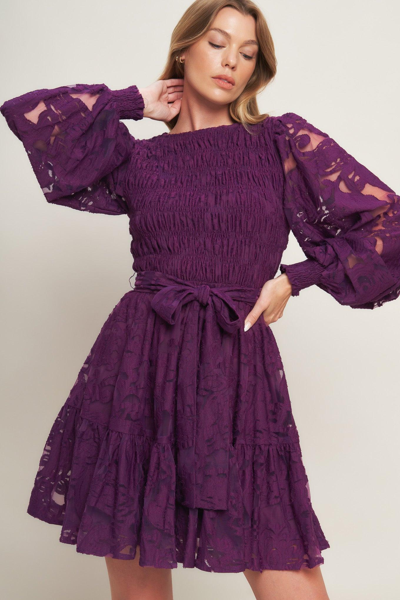 Woman wearing a purple lace dress with ruffled sleeves on a white background
