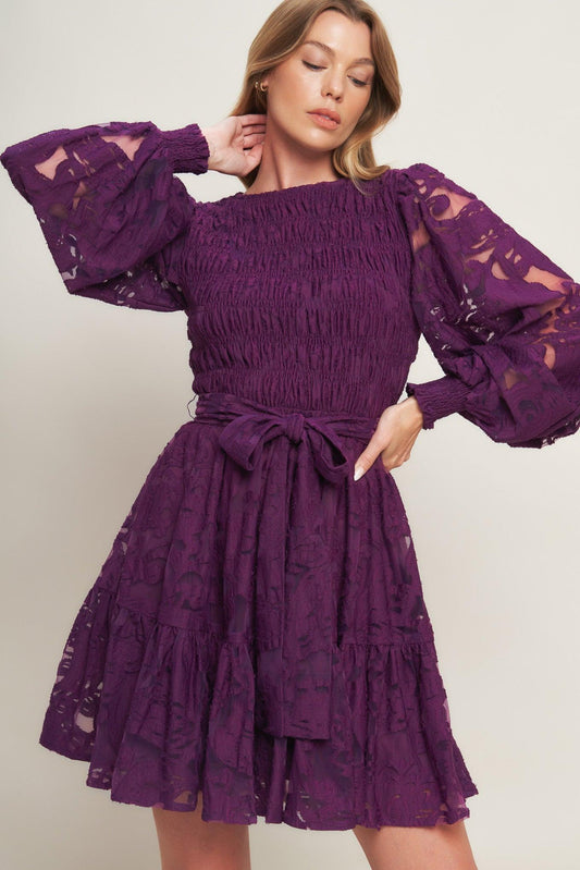 Woman wearing a purple lace dress with ruffled sleeves on a white background