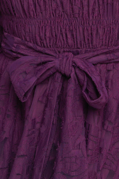 Close-up of a purple textured dress with a bow detail.