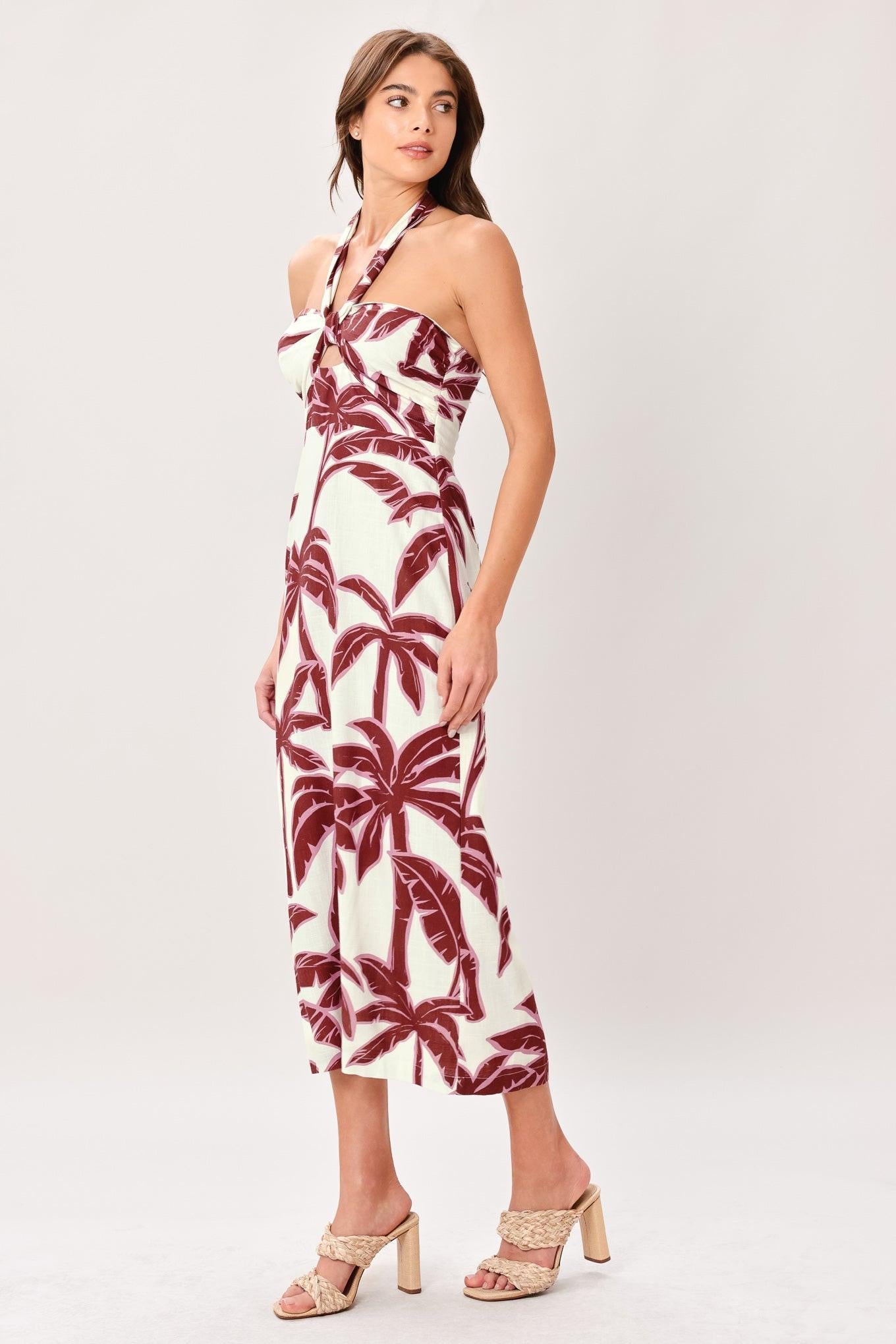 Woman wearing a palm tree patterned dress on a white background