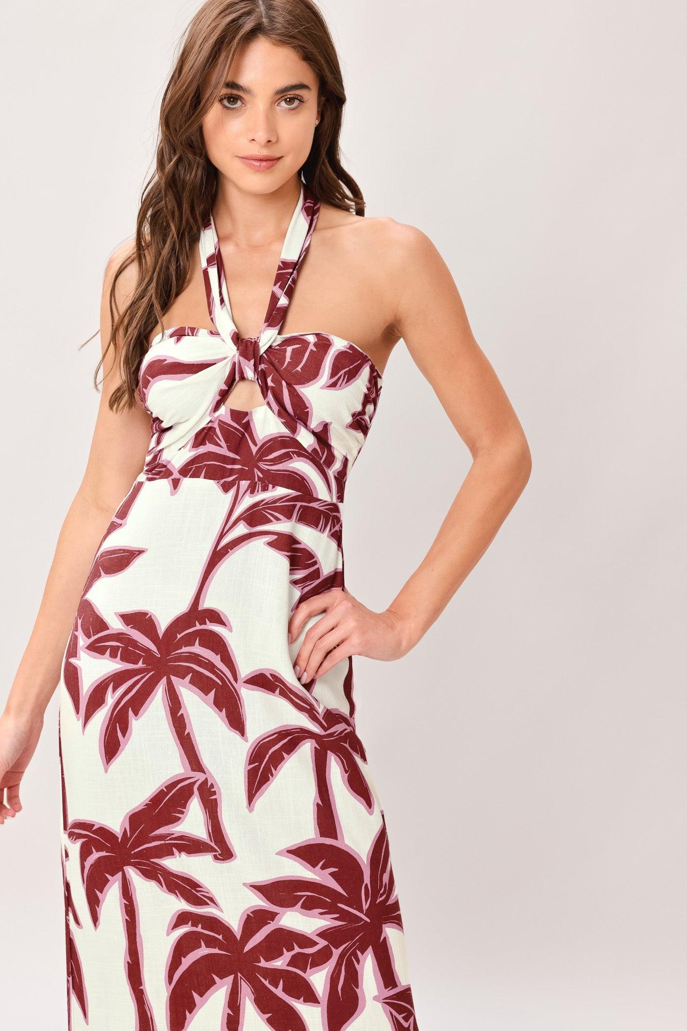 Woman wearing a white dress with red palm tree pattern on a light gray background