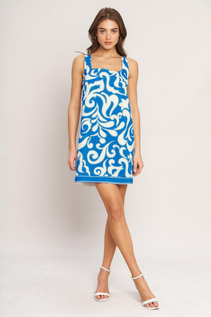 Woman wearing a blue and white patterned dress on a plain background