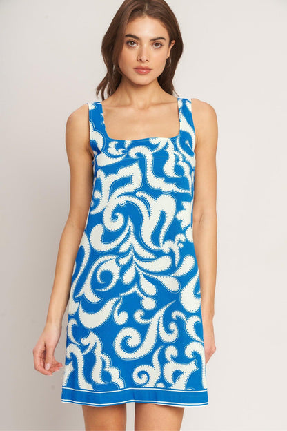 Woman wearing a blue and white patterned dress against a plain background