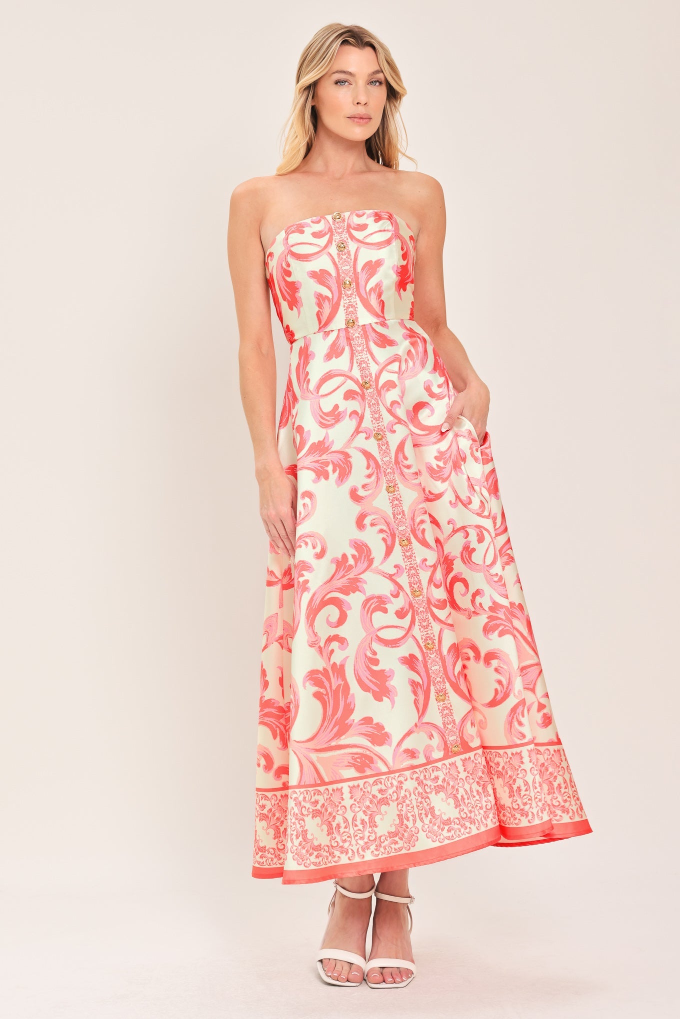 Woman wearing a strapless dress with pink floral pattern on a white background