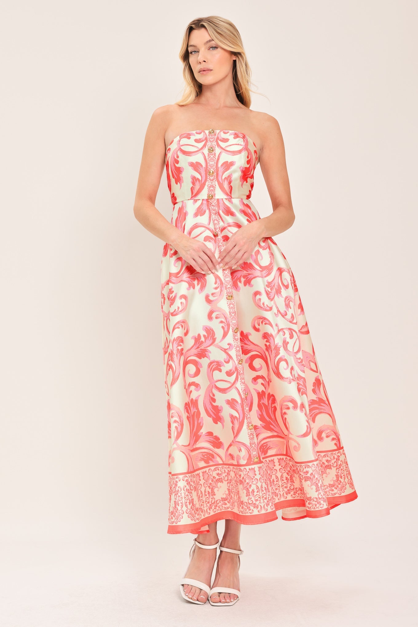 Woman wearing a strapless dress with pink and white floral pattern on a plain background