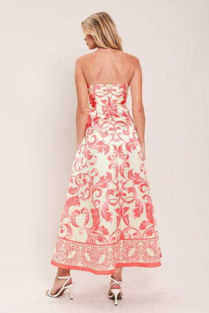 Woman wearing a strapless floral dress with pink and white pattern on a plain background