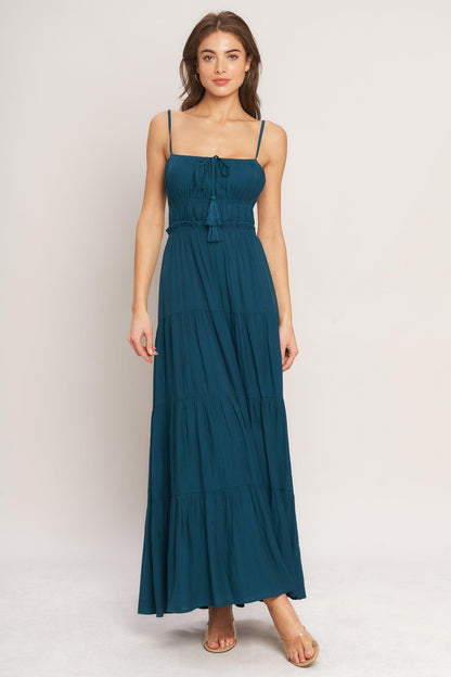 Woman wearing a teal maxi dress on a white background