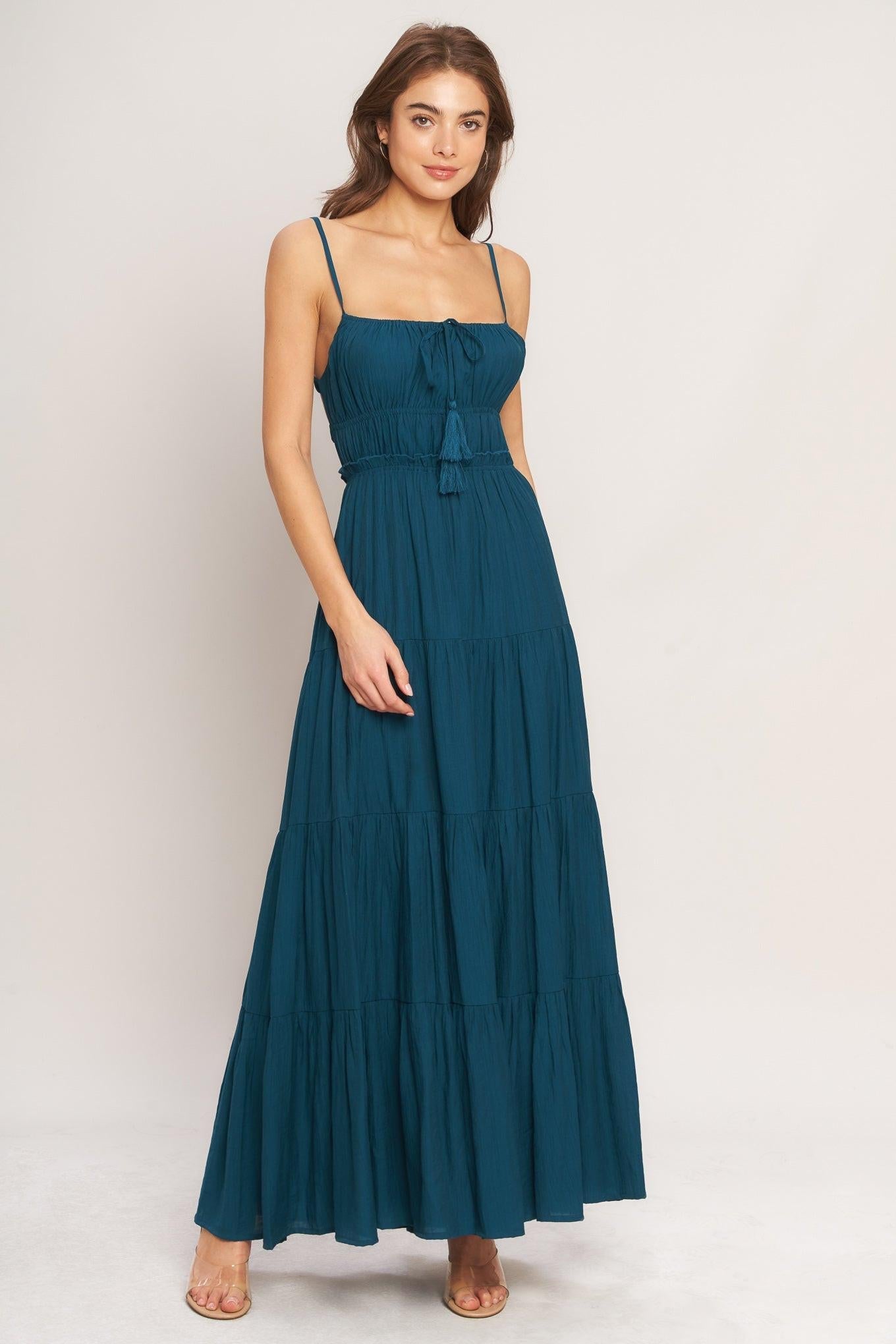 Woman wearing a teal maxi dress on a white background