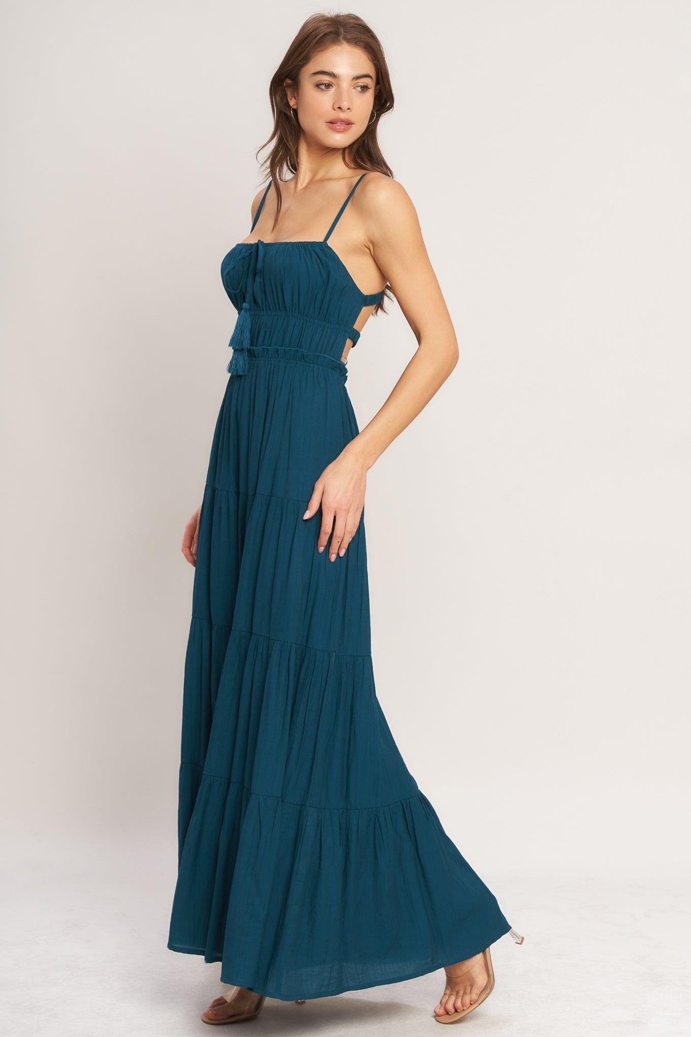 Woman wearing a teal maxi dress against a white background