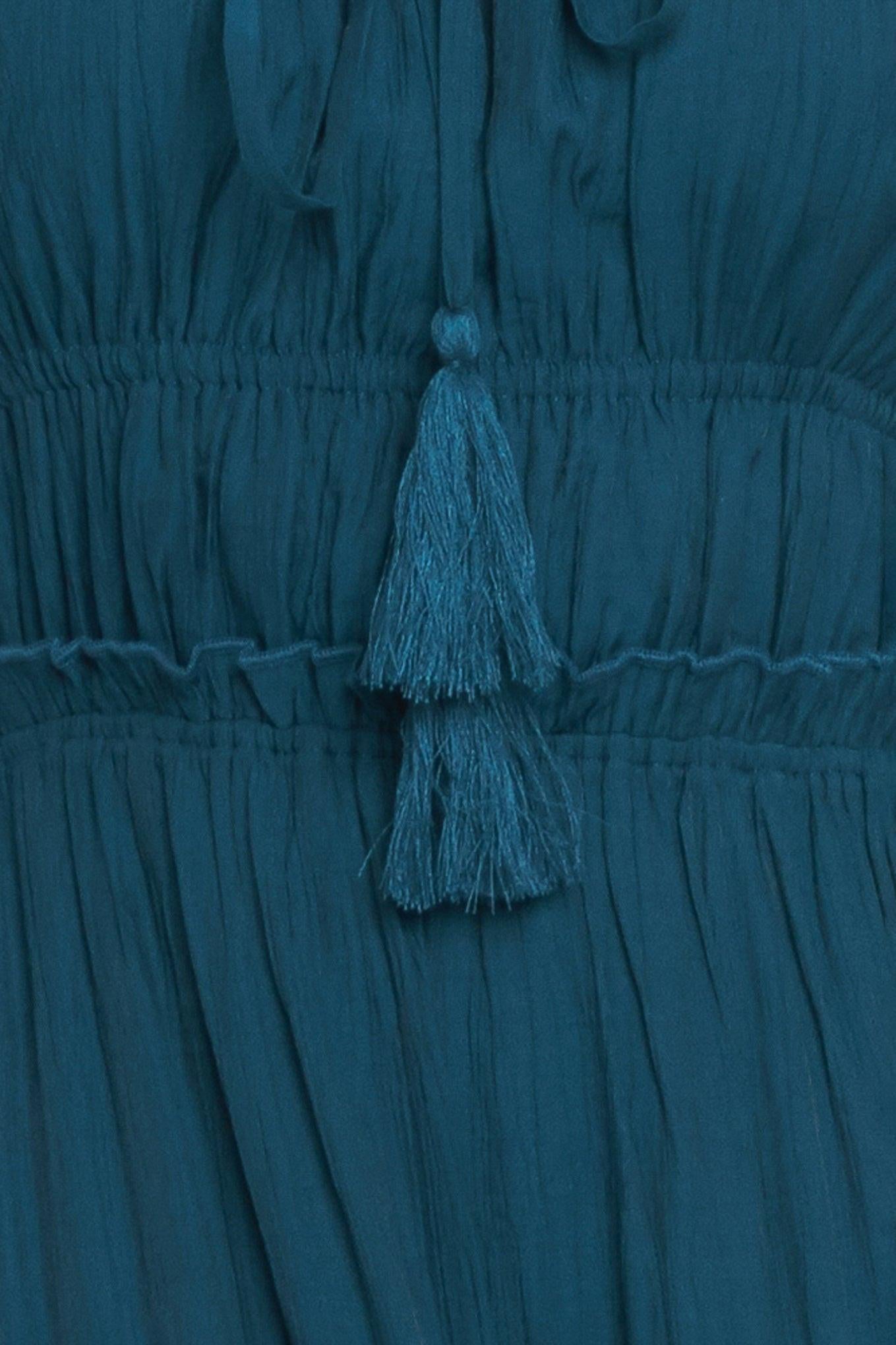 Teal dress with tassel detail on a matching background