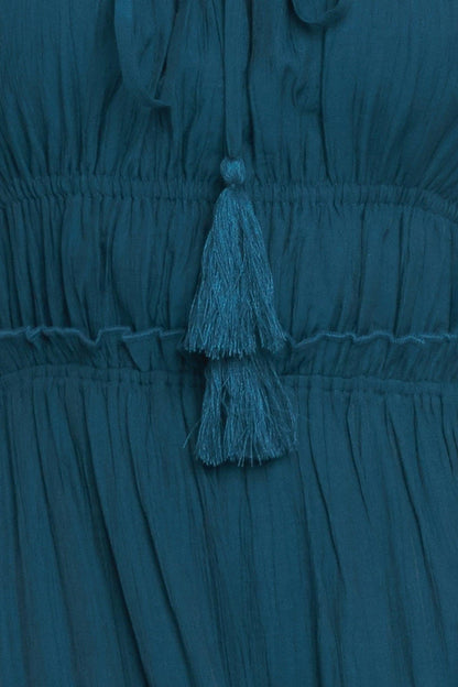 Teal dress with tassel detail on a matching background
